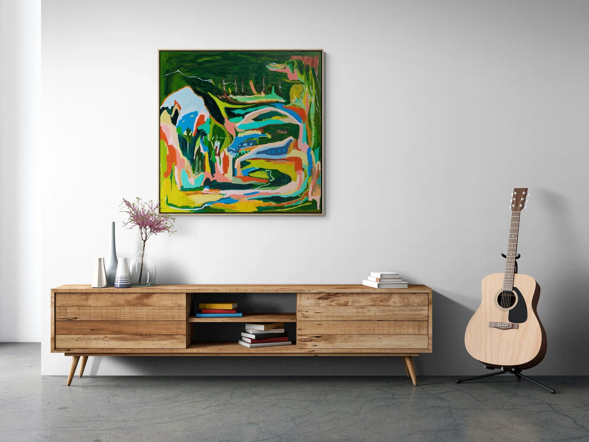 Abstract landscape painting By Alpana Rai displayed above a wooden media console with a guitar and decorative items to the sides, set against a white wall.