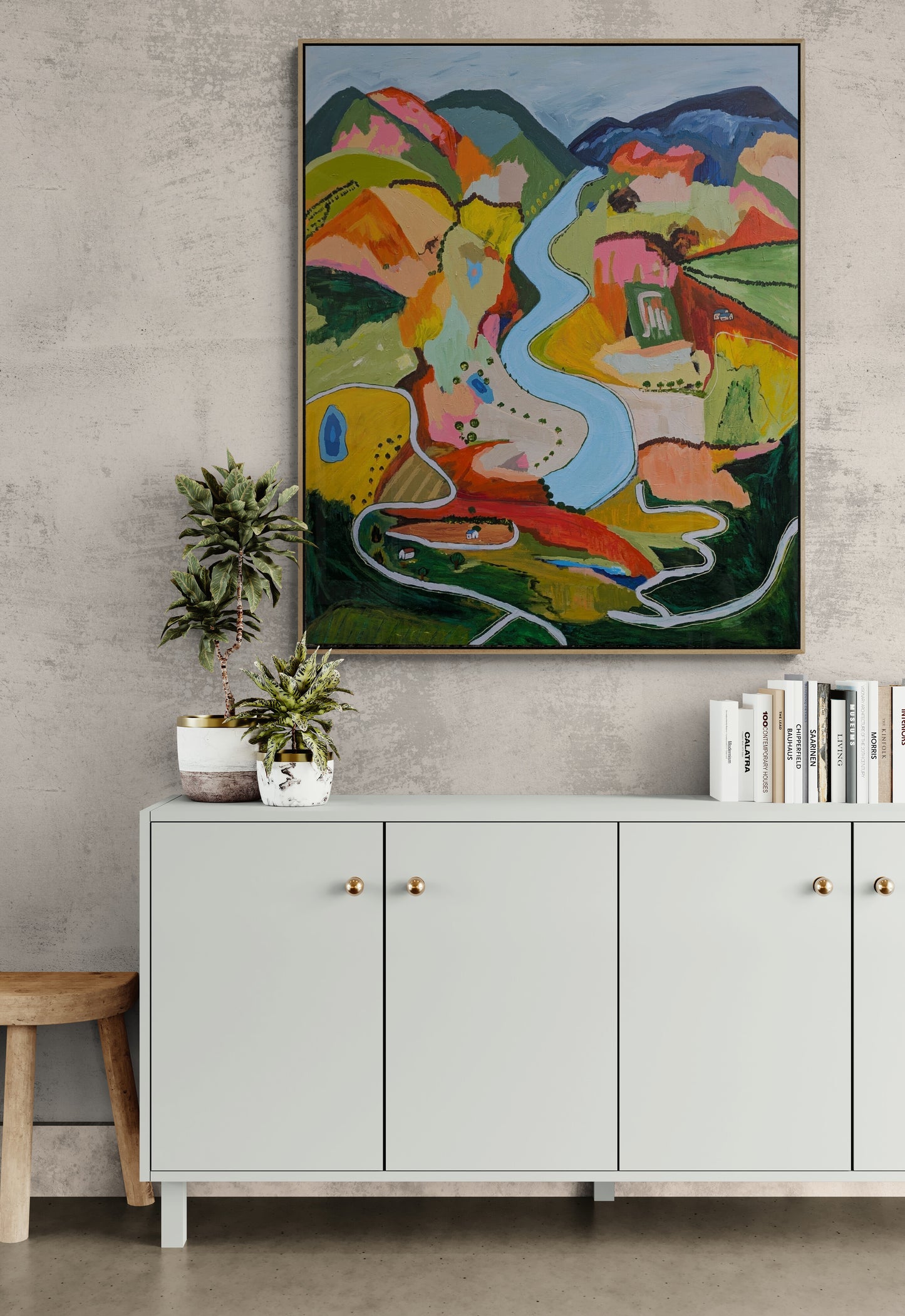 Abstract Landscape painting By Alpana Rai on a wall above a light gray cabinet with gold handles.